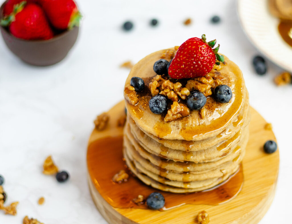 Naturally sweetened vegan pancakes fresh from the skillet, folded and stacked, with a drizzle of vegan buttermilk syrup.