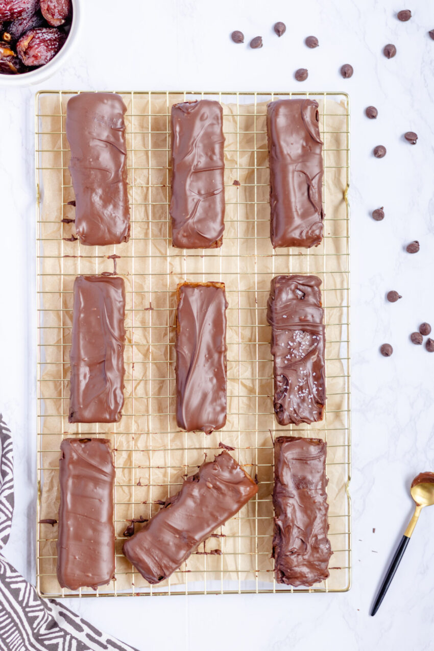 Close-up of homemade plant-based Twix bars made with layers of almond flour shortbread, date caramel, melted vegan chocolate on top, and some flaky sea salt.