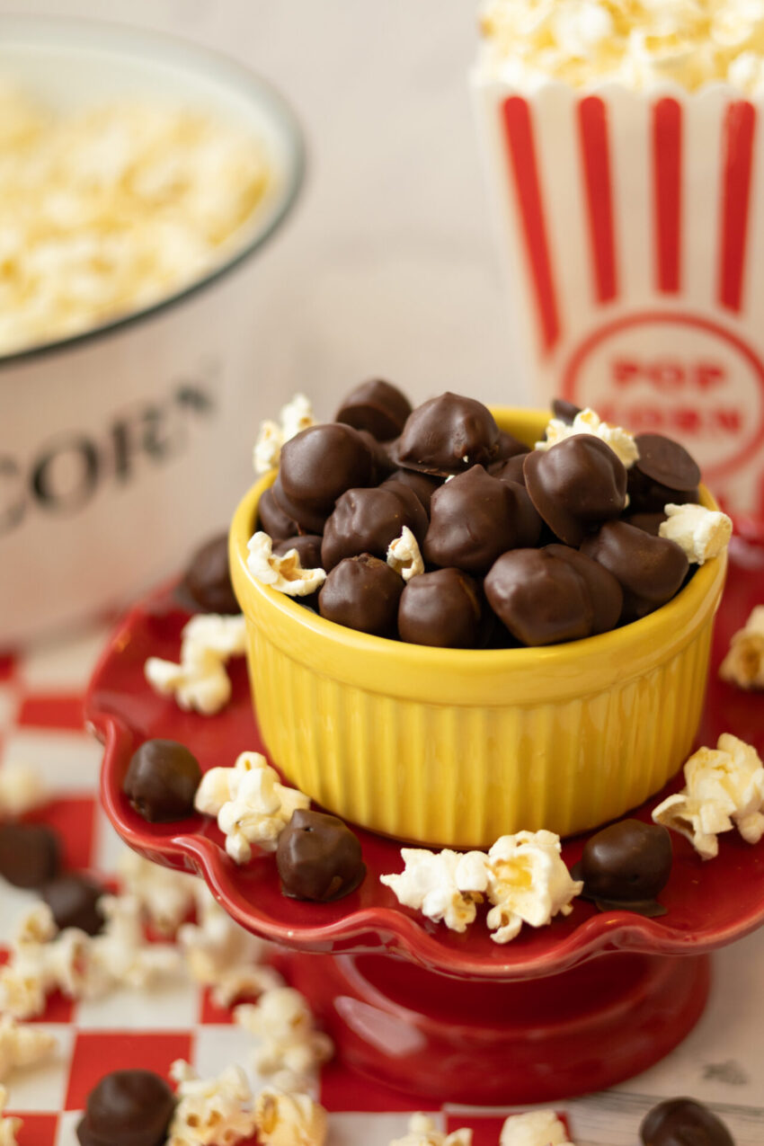 Bite-sized healthy cookie dough candies coated in chocolate surrounded by popcorn, ready to enjoy.
