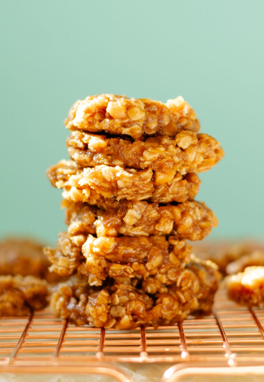Chewy no bake peanut cashew cookies on parchment paper, topped with chopped peanuts, stacked on top of each other.