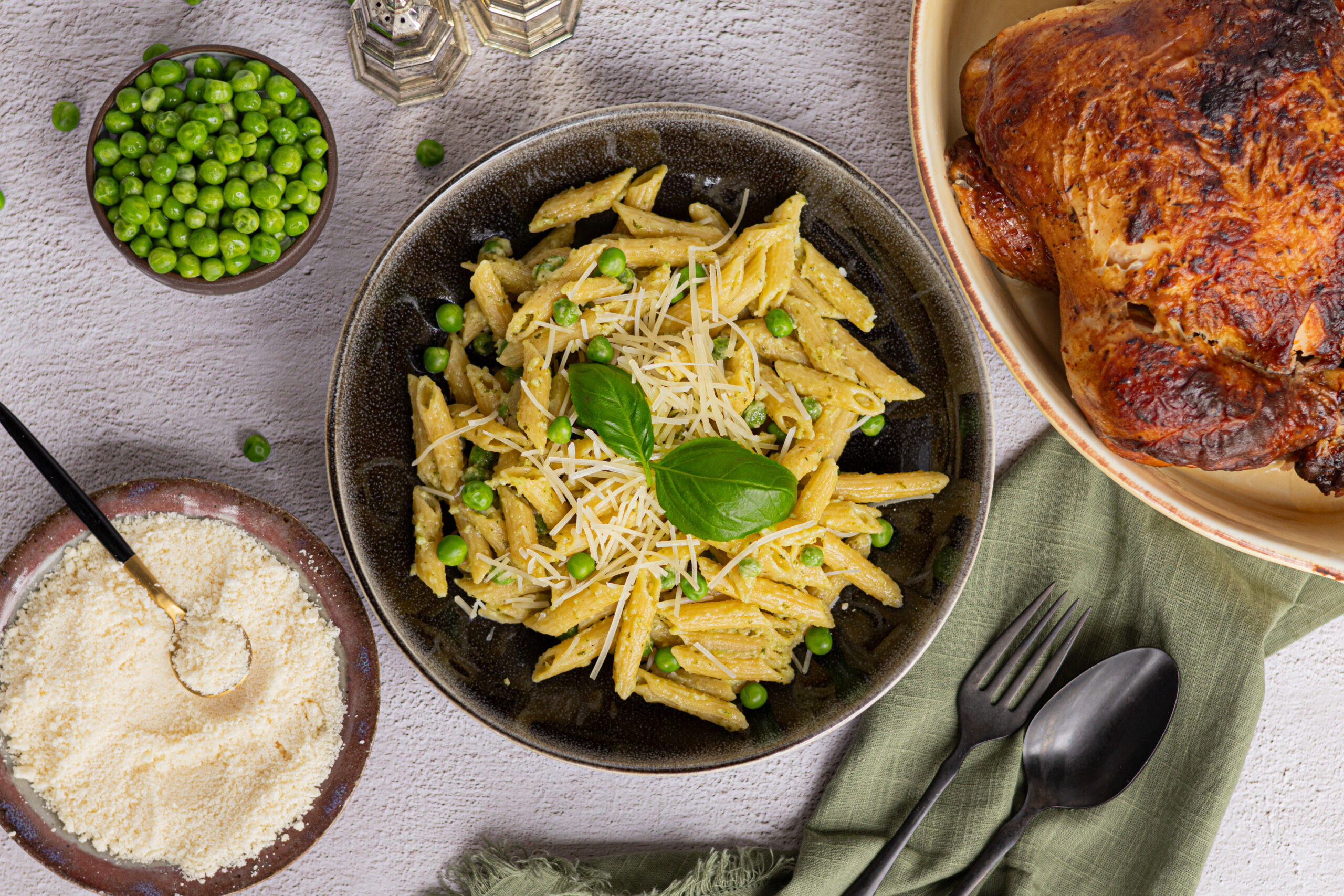 Creamy pesto pasta with peas topped with Parmesan and fresh basil, served with rotisserie chicken.